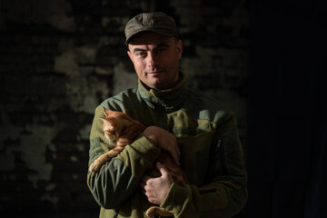 Portrait of smiling military man in olive uniform holding little red cat