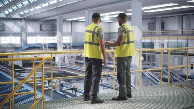 Delivery Station Warehouse Associates Having a Conversation at a Modern Logistics Center. Workers Using Tablet to Manage the Automated Conveyor Belt Load, Prepare Online Shopping Orders for Delivery
