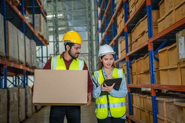Warehouse worker uses digital tablet for checking stock in a large distribution warehouse.