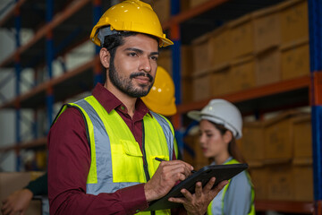 Warehouse worker uses digital tablet for checking stock in a large distribution warehouse.