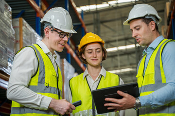 Warehouse employees reading a clipboard ann checking packages on shelf in a large logistics centre.
