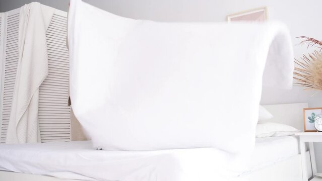 caucasian woman making her bed in the morning. young millennial woman doing her morning routine at the bedroom