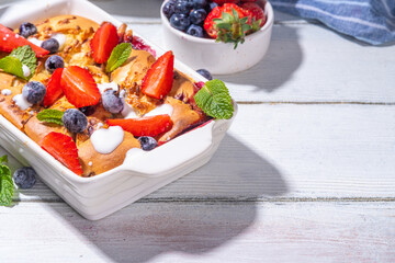 Sweet summer berry cobbler pie, homemade sponge cake with sugared blueberry and strawberry, served with vanilla ice cream ball, on sunny white wooden kitchen table