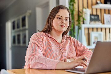 A pretty plus-size woman working over the laptop in her bright living room.