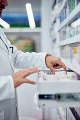 Obraz na płótnie Canvas Male pharmacist taking a box of medicine from the drawer.