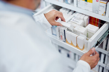 Close-up of a drawer with boxes of medicine, pharmacist taking one of them.
