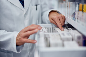 Close-up of a male pharmacist checking drawer with a medicine.