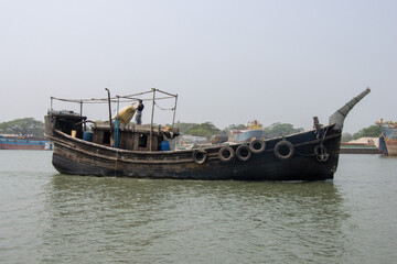 Southeast Asian fisher boat running through a river. Old wooden fishing trawler side view....