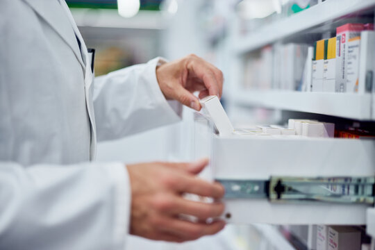 Side view of an pharmacist, taking a box of medicine, dressed in a white uniform.