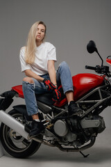 Obraz na płótnie Canvas Shot of young blond dressed in casual clothing and modern bike in studio.