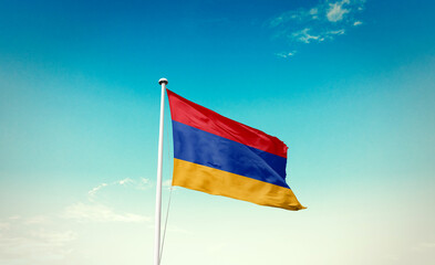 Waving Flag of Armenia in Blue Sky. The symbol of the state on wavy cotton fabric.