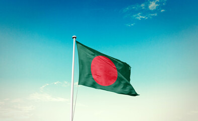 Waving Flag of Bangladesh in Blue Sky. The symbol of the state on wavy cotton fabric.