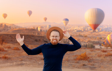 Fototapeta na wymiar Happy man tourist in hat with hot air balloons in Cappadocia Turkey.