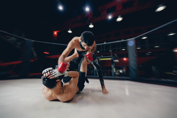 Fototapeta na wymiar Boxers fighter finishes off enemy in MMA ring octagon, dark background spot light