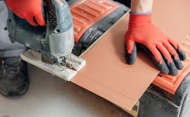 Professional worker is installing laminated or parquet on floor, man cuts wooden tiles
