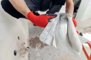 Master working with plasters on white walls and putty screeds after installing drywall