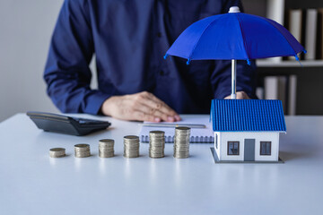 Fototapeta na wymiar insurance business The agent spreads the umbrella on the house. The concept of preventing health accidents and natural disasters, a close-up image.