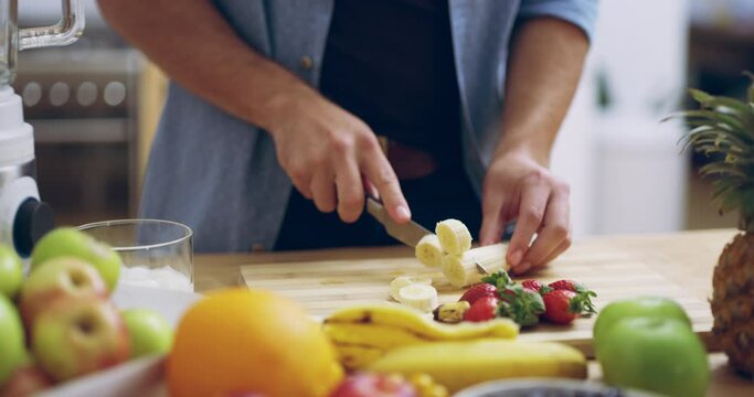 Hands, fruit and a man cutting a banana in the kitchen of his home for health, diet or nutrition. Food, breakfast and wellness with a healthy male person in his house for organic meal preparation