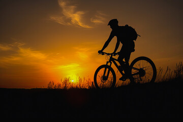 Fototapeta na wymiar Cyclist on mountain bike riding silhouette in sunset light. Cyclist in motion. Young sport man rides along countryside road. Generative AI