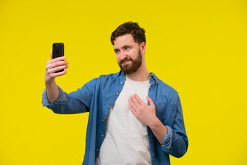 Happy young man video calling, talking online with mobile phone, saying hello to smartphone camera...