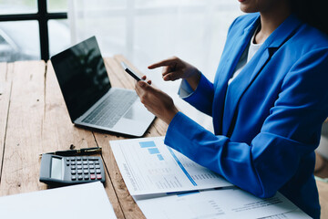 Busy businesswoman wearing a suit busy with work workaholic while sitting at work clear paperworks with documents and talk on the phone on your smartphone hear the hustle and bustle, busy concepts.