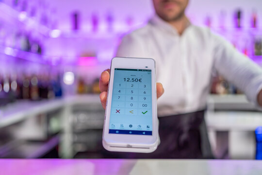 Crop bartender offering POS machine to pay for order