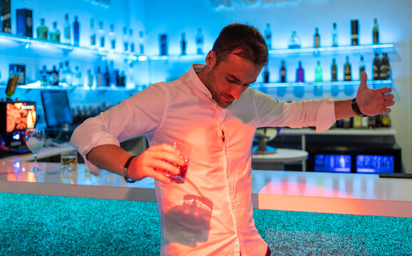 Male bartender spilling cocktail on shirt in bar