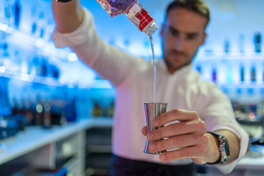 Blurred male bartender pouring alcohol into jigger