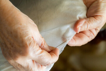  Close-up, senior woman's hands sewing with a needle
