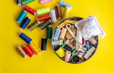 Sewing box isolated on yellow background with spools of threads