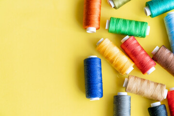 Spools of sewing thread with assorted colors on a yellow background.