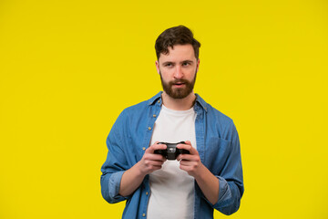 Close up photo of nervous scary fan of video games, he is holding a console, isolated on bright yellow background, copyspace