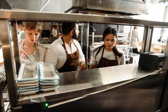 Confident busy multinational chefs cooking in kitchen