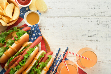 4th of July American Independence Day traditional picnic food. Hot dog with potato chips and cocktail, American flags and symbols of  USA Patriotic picnic holiday on white wooden background. Top view