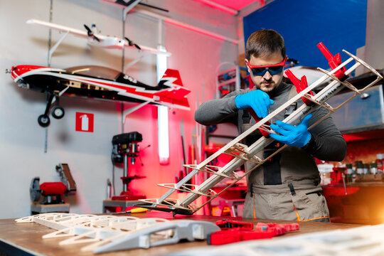Professional male engineer or technician working on drone details in lab. Aircraft capable of GPS surveillance. Carbon.