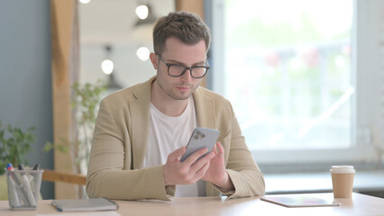 Young Businessman Using Smartphone at Work