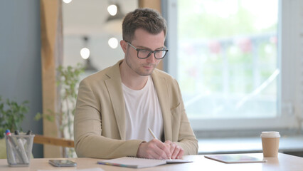 Young Businessman Writing at Work, Paperwork