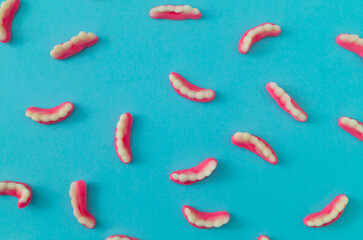 Creative pattern made of pink and white gummy candies on light blue background. Minimal trendy...