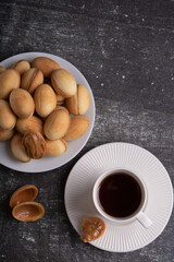 Photo of a pile of nuts and condensed milk on a plate and a cup of coffee