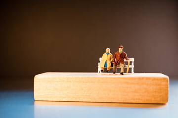 Miniature elderly people sitting with mini house and year 2022 wooden block using as job retirement and family concept