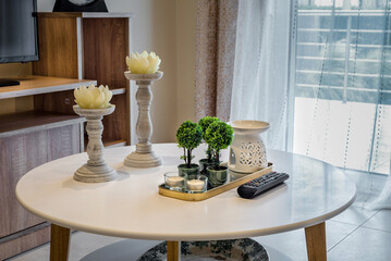 Indoor interior design detail element.  Table with with two candlesticks with candles in form of lotus flower and other decorations.