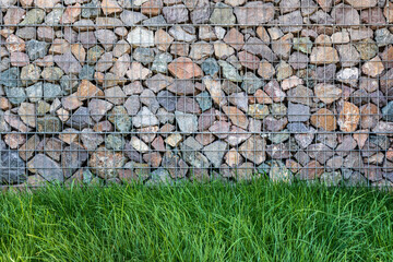 Wall of gabions and fluffy lawn grass in front of it, copy space.