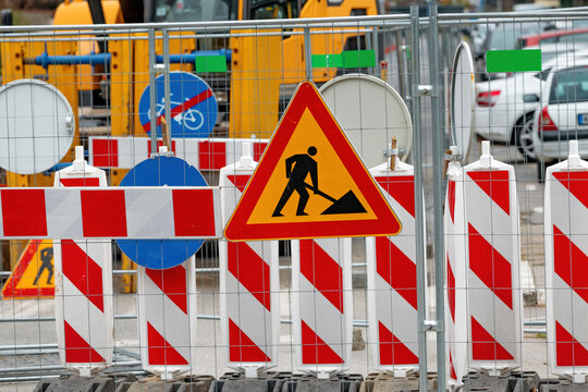 Men at work road sign at construction site during city street road maintenance