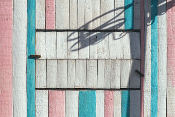 Pastel color painted wooden shed with shadow of basketball hoop