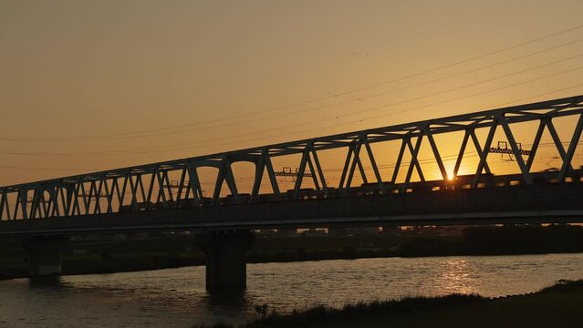 夕暮れの鉄橋を渡る電車の風景