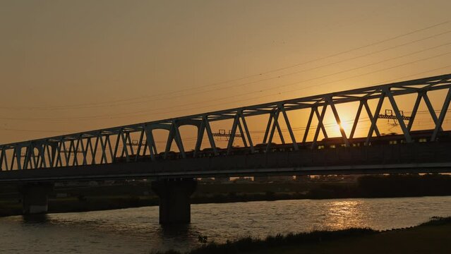 夕暮れの鉄橋を渡る電車の風景