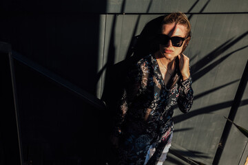Fototapeta na wymiar a fashionable woman stands in the shadows against a black wall