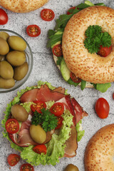 Sesame bagels with tomatoes, ham and olives