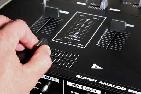 hand on dj mixer crossfader (detail closeup) analog music equipment, super macro, knobs and volume adjusters