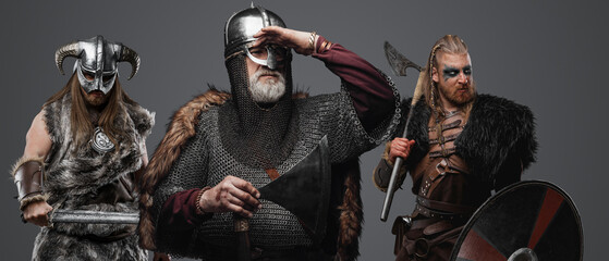 Shot of old man barbarian with two comrades looking away against grey background.